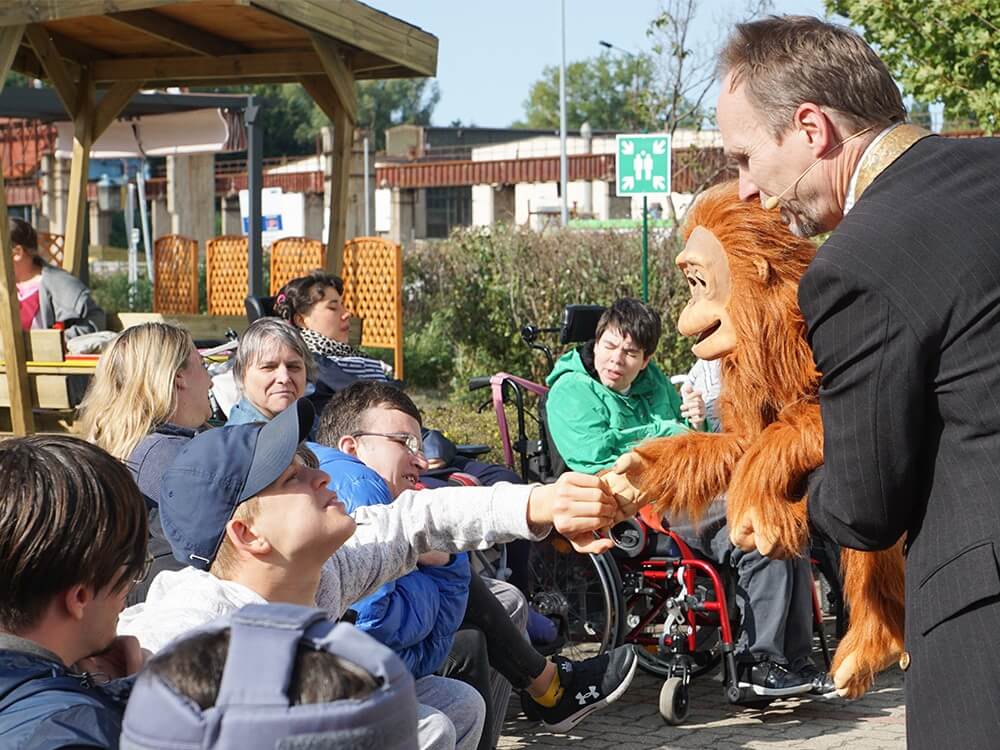 Bühnenkünstler lässt eine Person aus dem Publikum die Bauchsprechpuppe anfassen