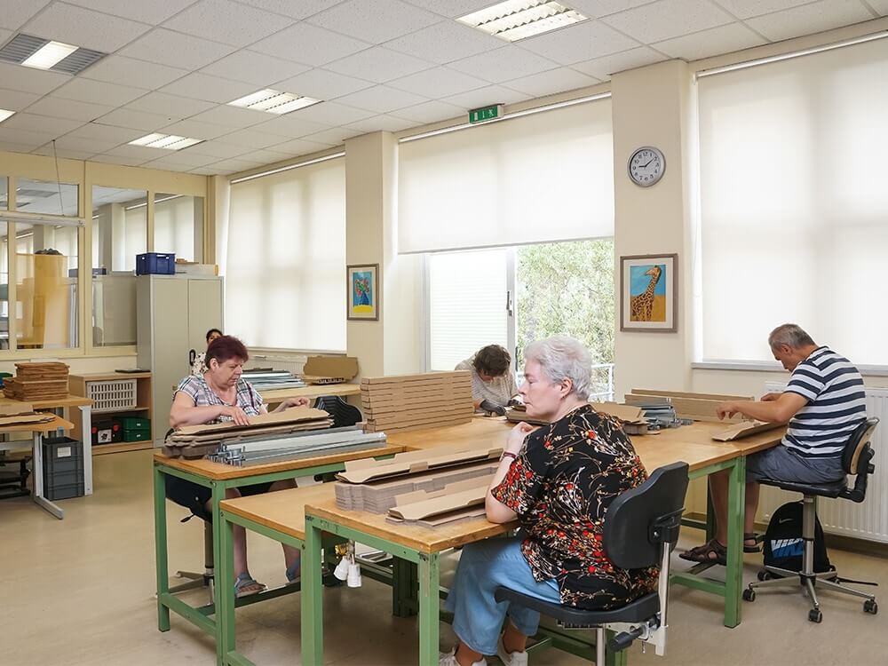 Mitarbeiter*innen falten Verpackungskartons