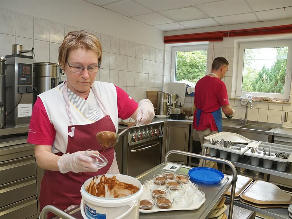 Eine Person füllt in der Küche Pudding in eine Schale