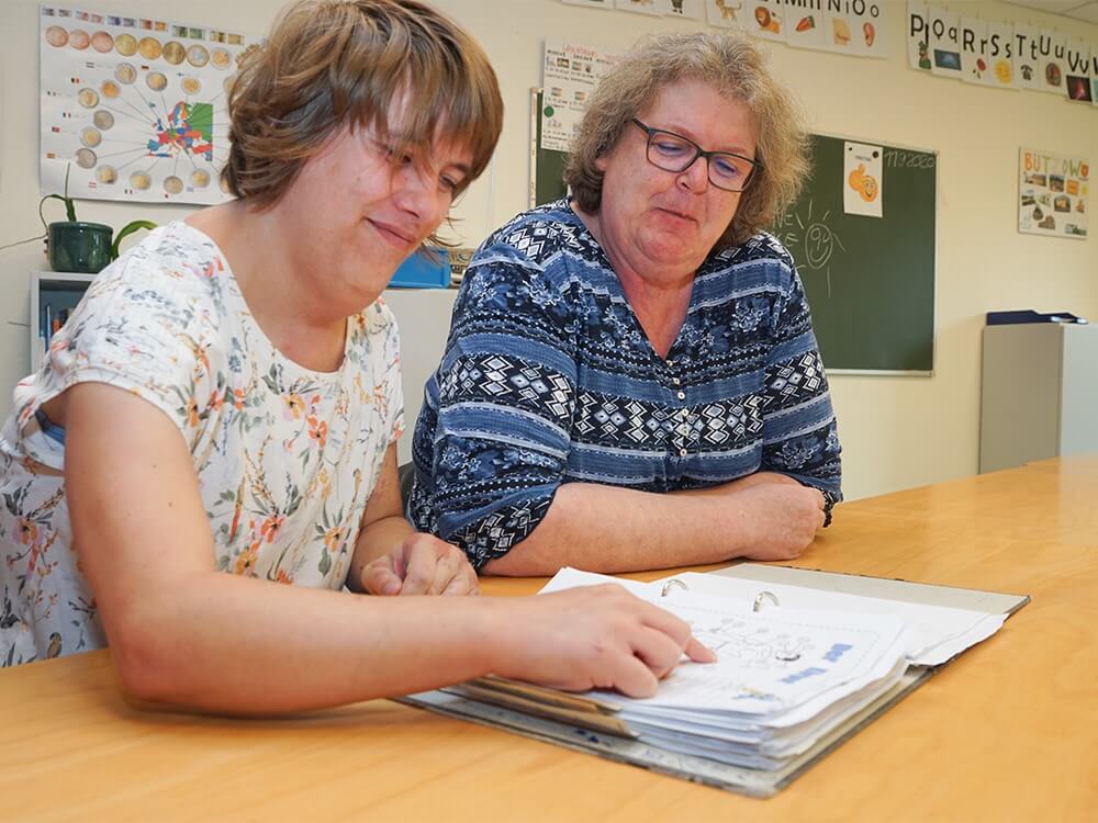 Zwei Personen blättern in einem Hefter