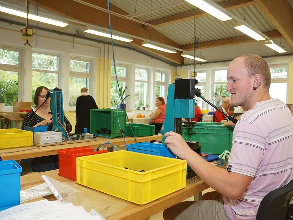 Mitarbeiter*innen arbeiten an Werkbänken