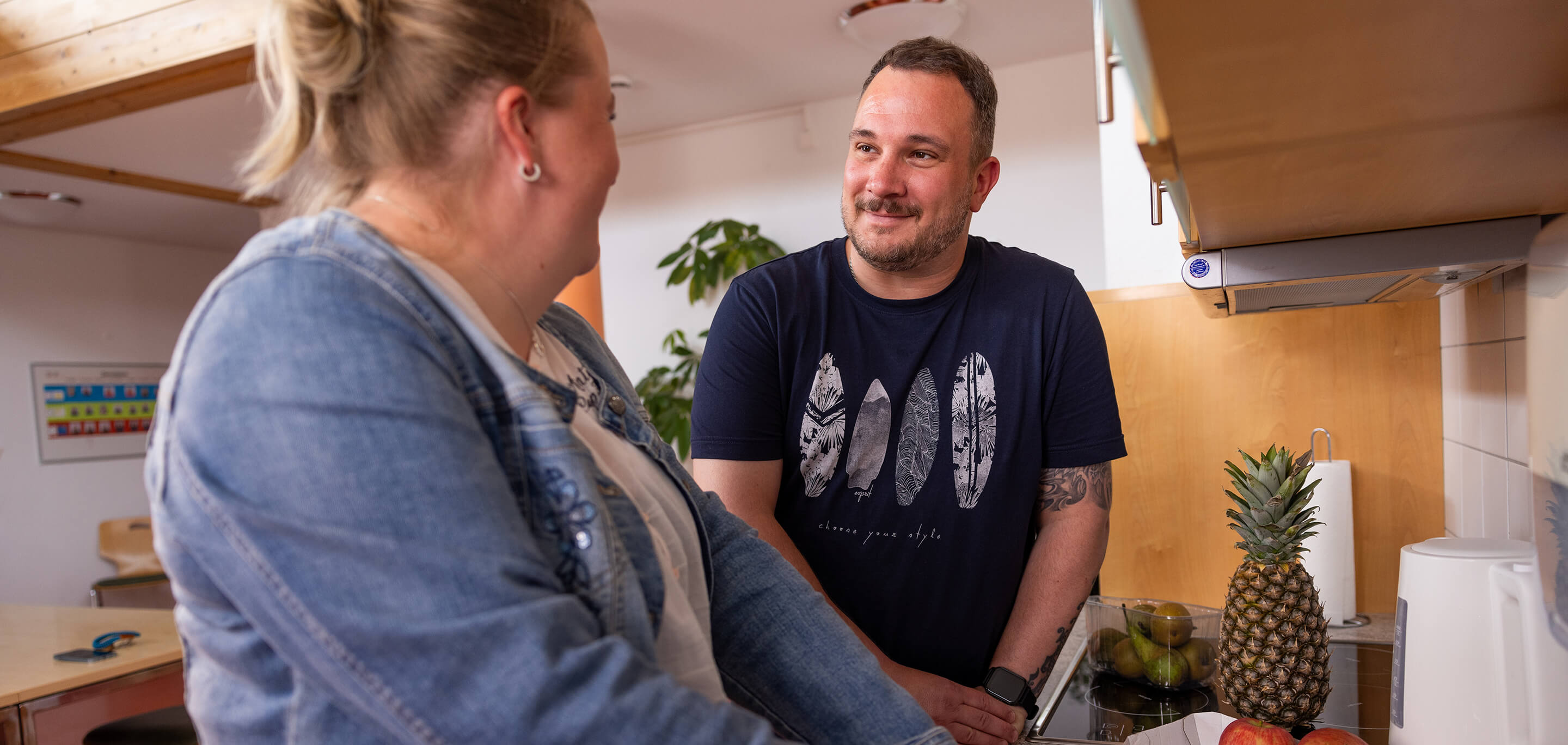 Eine Frau schneidet Obst in der Küche, während sie einen Mann dabei anschaut.